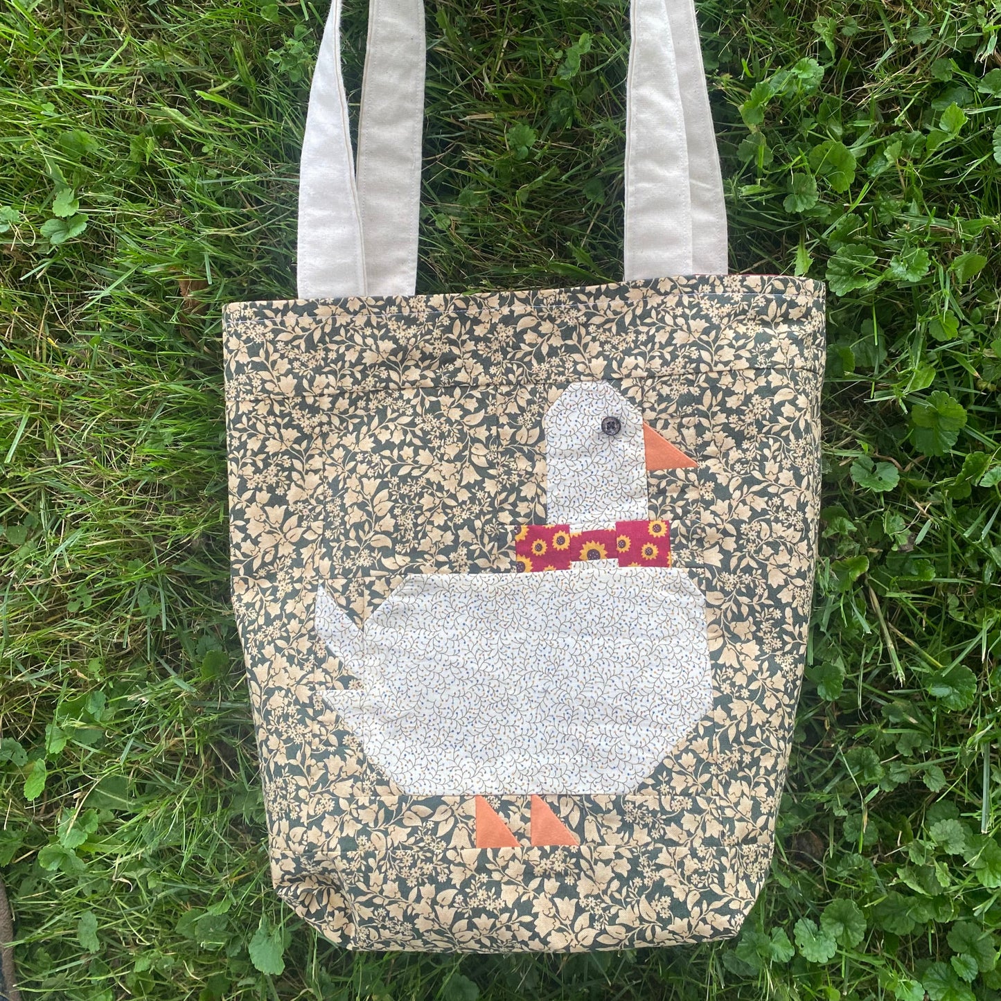 Tote bag with a duck design on grass
